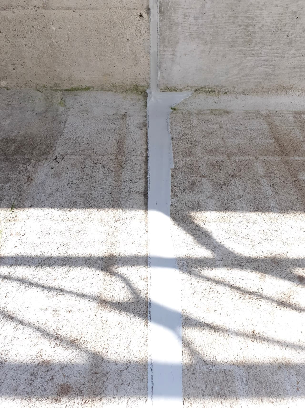 Hellgraue fertige Abdichtungslinie in einer rauen Betonfuge