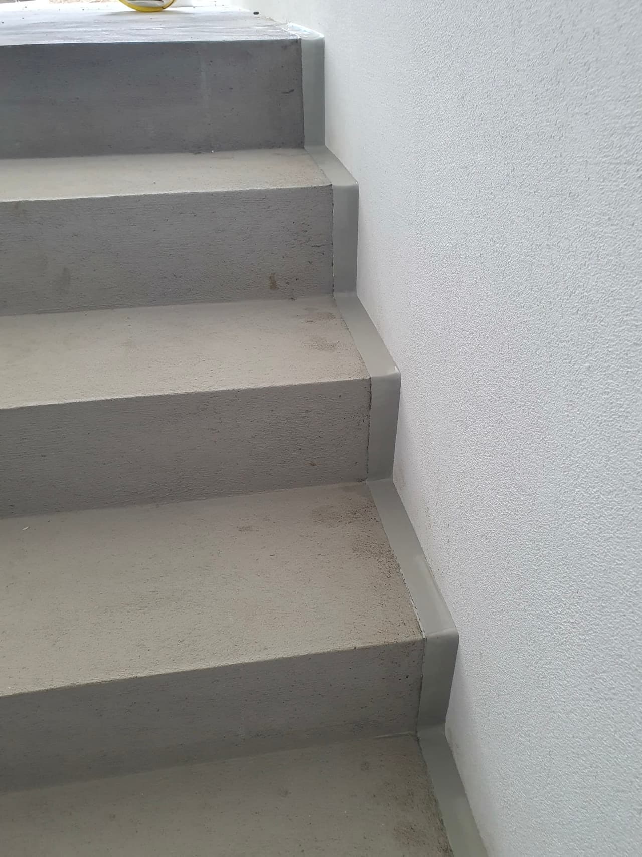 Graue fertige Fuge entlang der wandseitigen Kante einer Betontreppe
