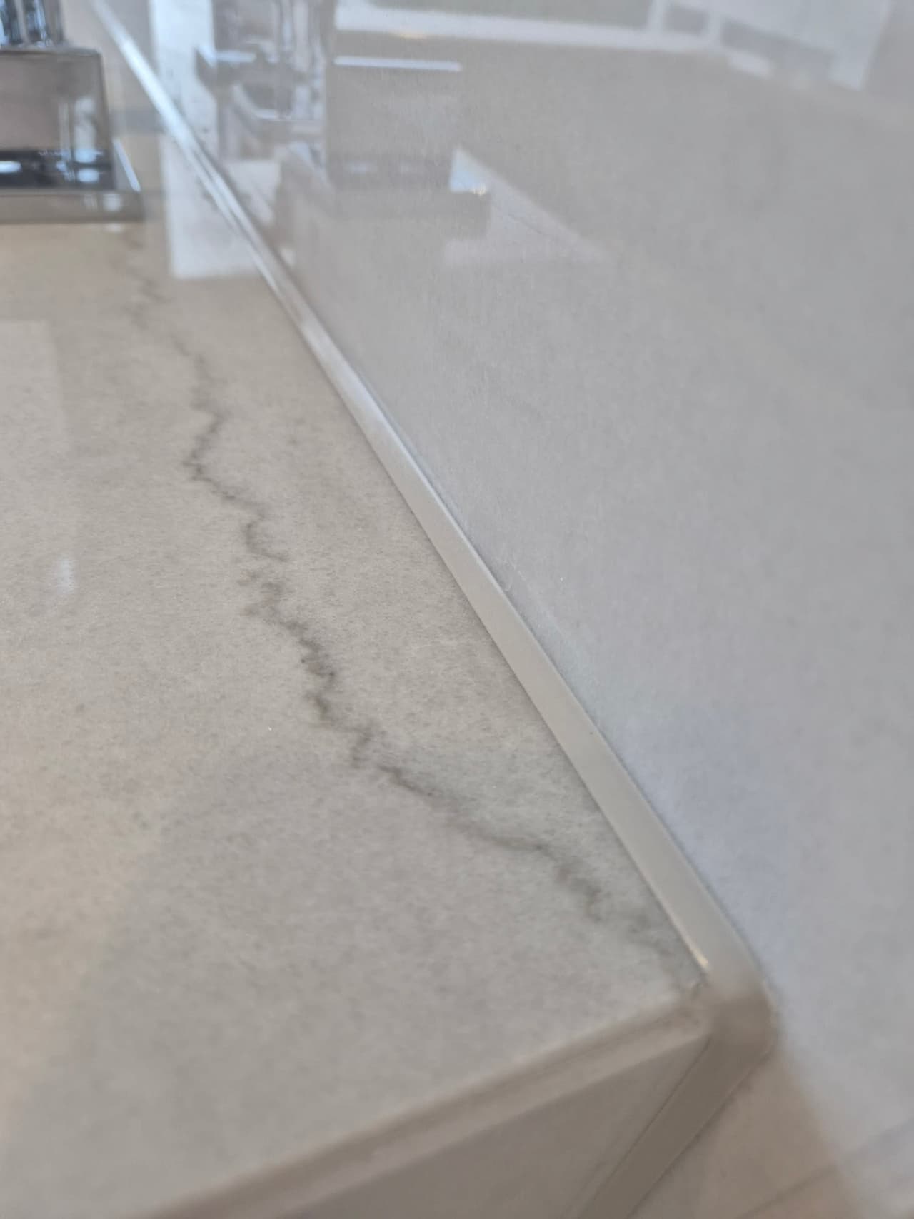 Nahaufnahme einer hellen Sanitärfuge entlang einer Badmöbelplatte und Wand